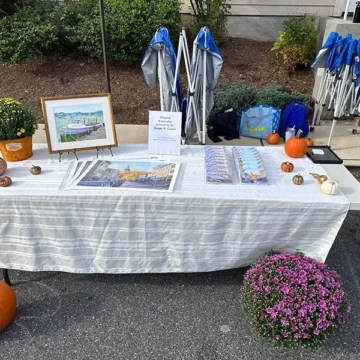 Community event table with framed art, pumpkins, and promotional materials