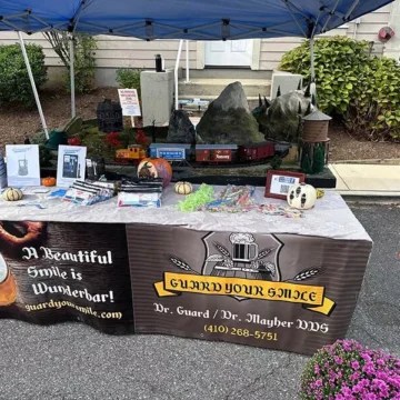Dental booth under blue tent with &ldquo;Guard Your Smile&rdquo; banner and giveaway items