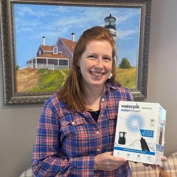 Woman smiling while holding Waterpik product box